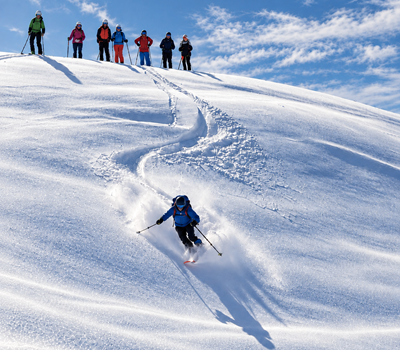 pulverschnee-abfahrt-im-sonnigen-alpenhang