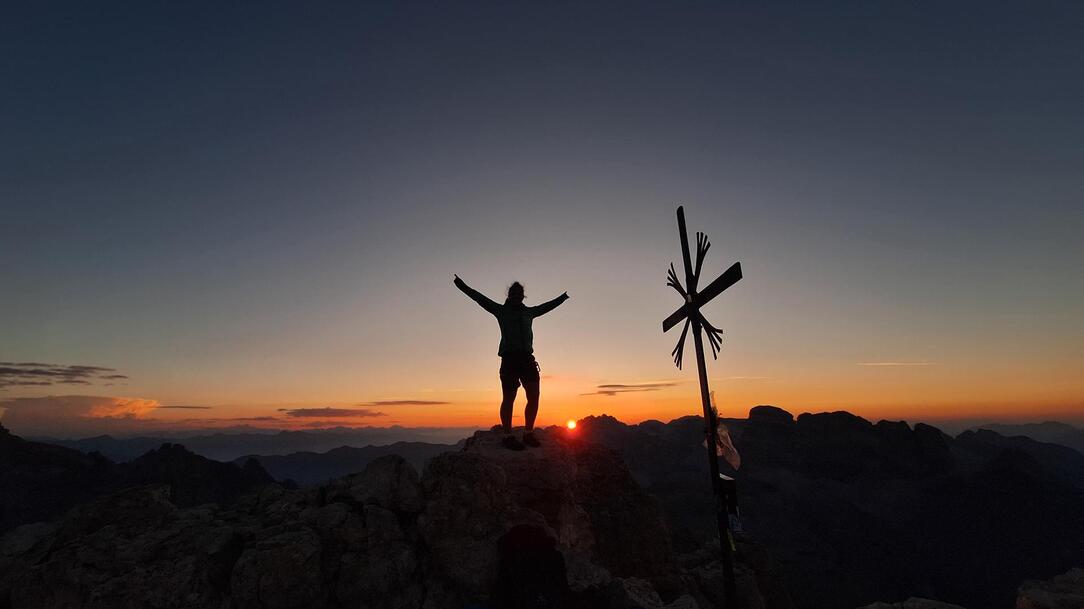 Woman at the peak at sunset