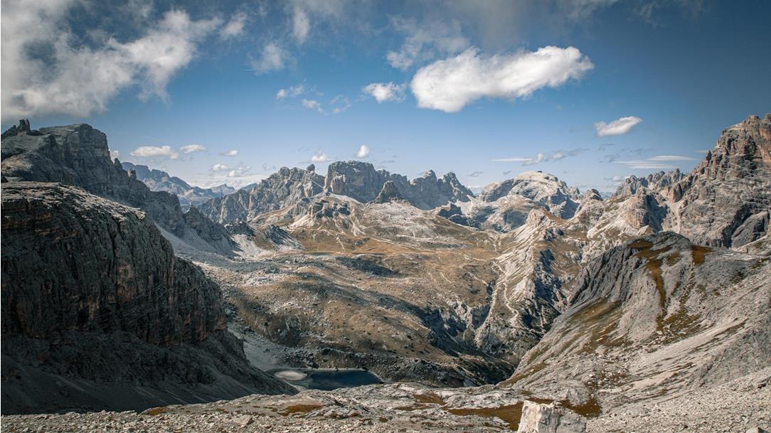 Vast, high-alpine panorama  featuring barren rocky landscapes,  valleys, and small mountain lakes  during a week of trail running in the Dolomites.